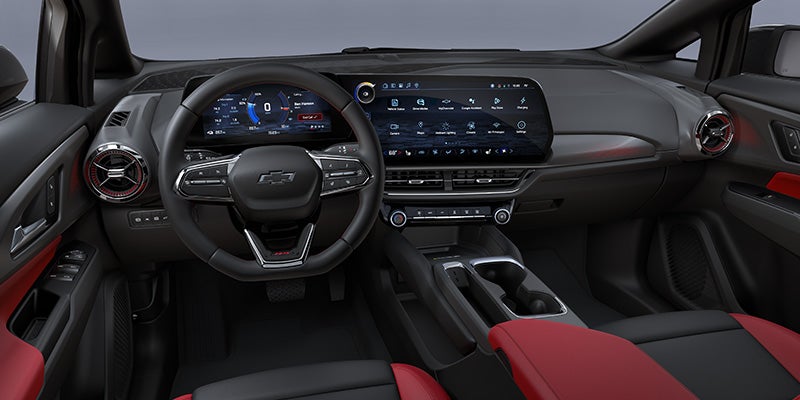 Modern Chevrolet interior dashboard featuring dual digital displays, a flat-bottom steering wheel, and red accent trim.