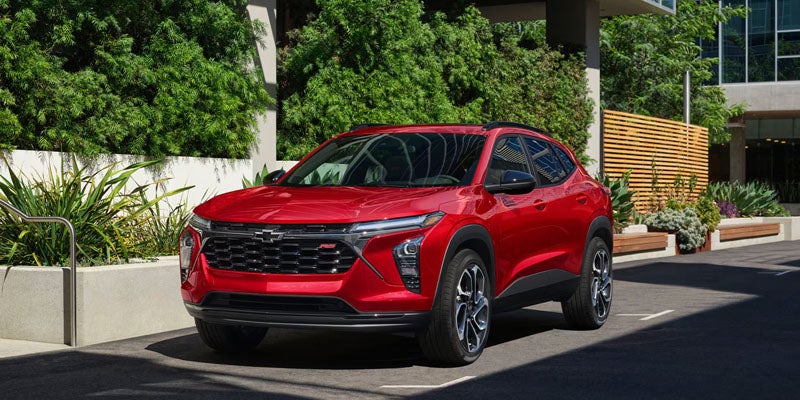 A bright red Chevrolet Trax RS compact crossover parked in a modern urban plaza.