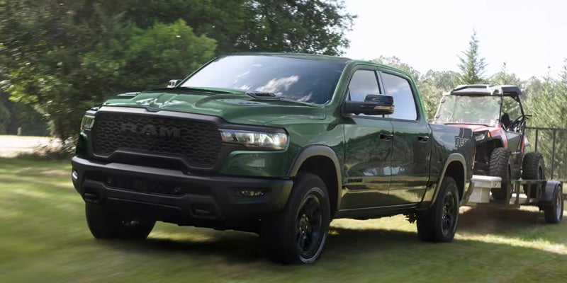 Green 2026 RAM 1500 towing a tractor in Victor, NY